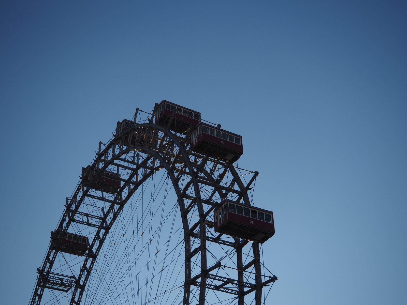Vienna ferris wheel top half in front of blue sky.
