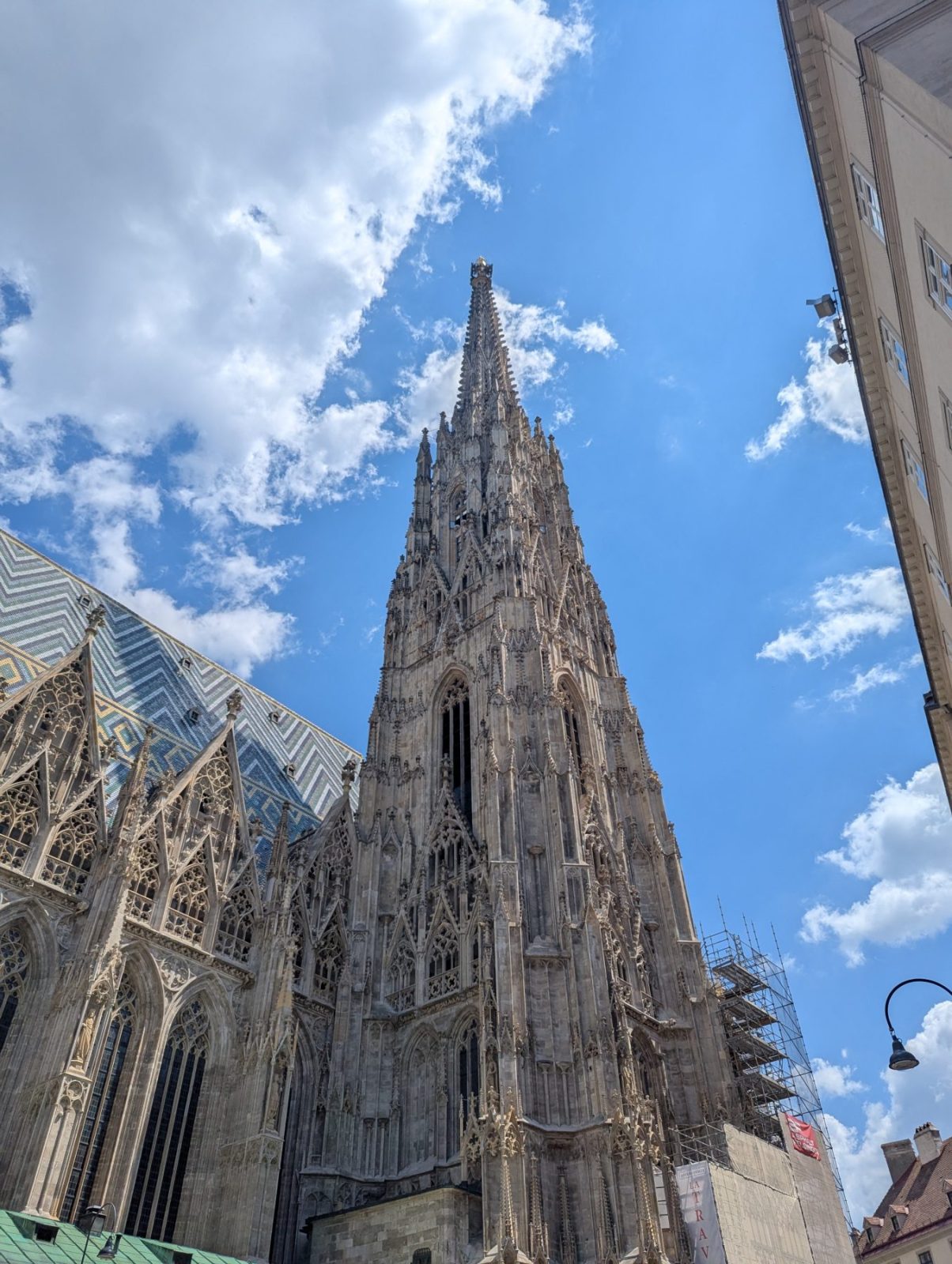 View of the Gothic Stephans Cathedral from the ground. Highlight is the spiral tower. Blue sky and a few clouds in the back.