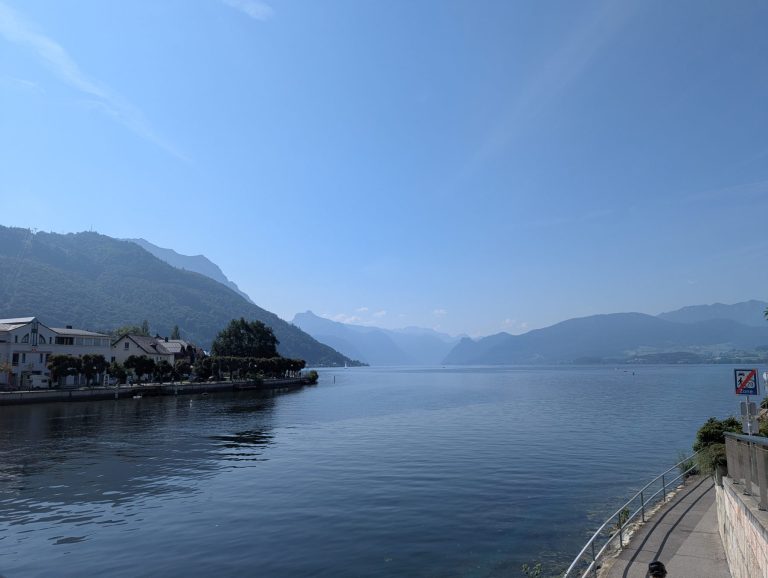 View of vast lake in Gmunden with small green mountains in the background and a light mist.