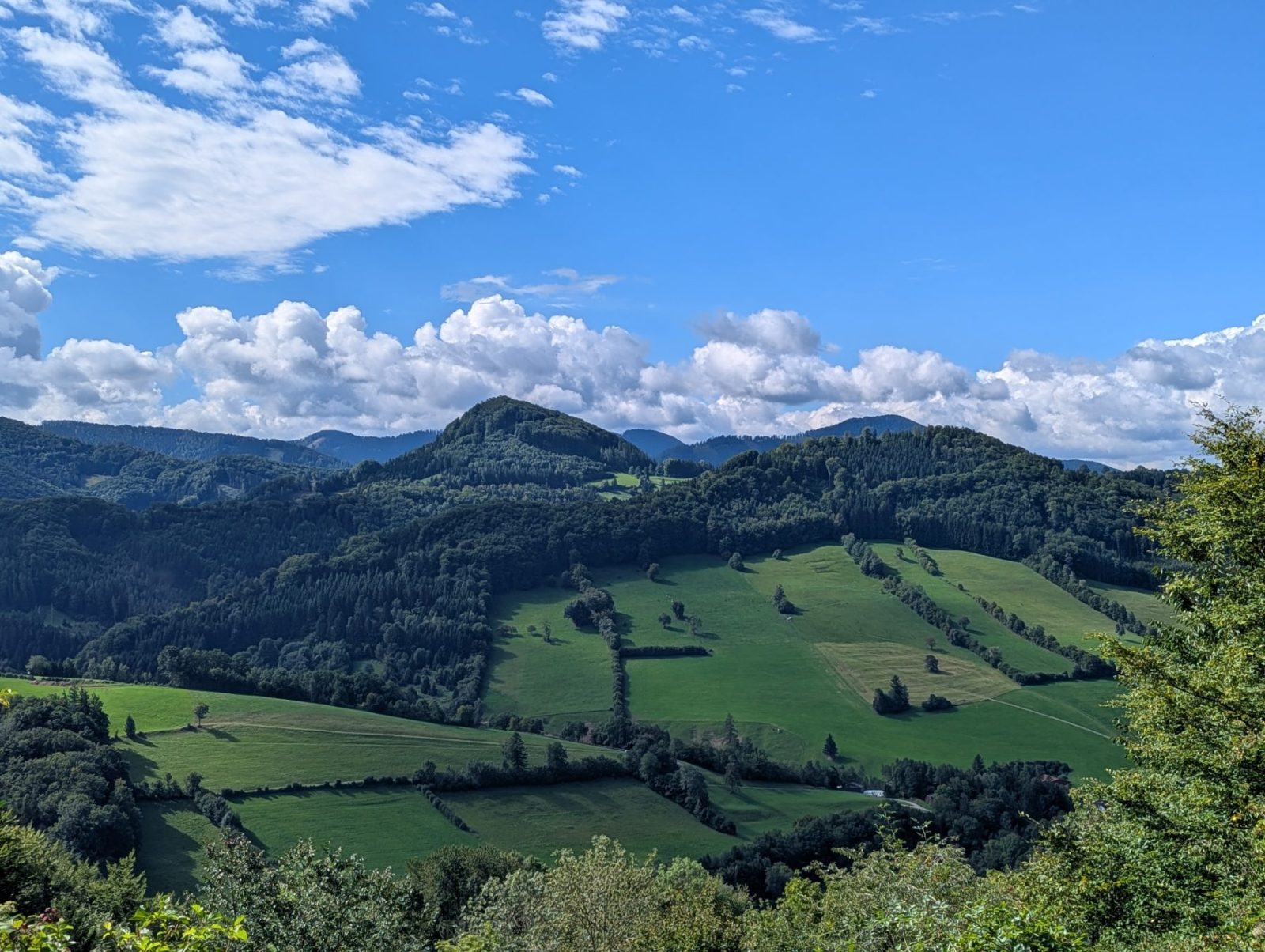 View of the valleys in the Pielachtal. Green valleys and hills under blue sky with clouds.